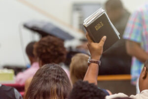 African American Man at Church with a Bible Raised